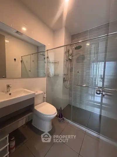 Modern bathroom with glass shower and sleek fixtures in contemporary apartment.
