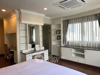 Spacious bedroom with built-in desk and ample natural light in modern apartment.