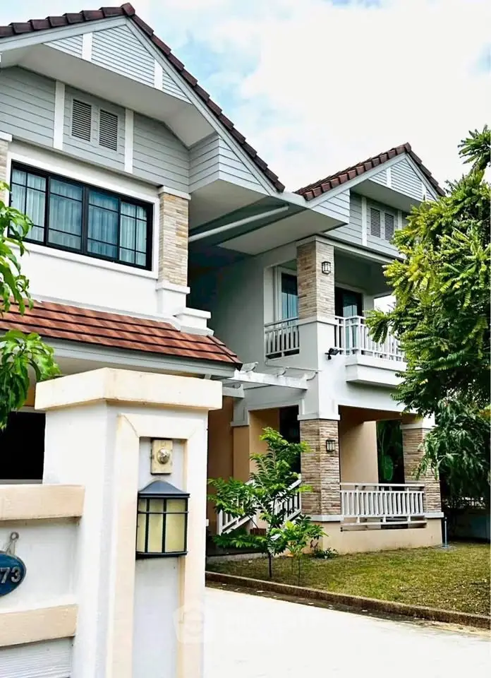 Charming two-story house with modern design, lush greenery, and inviting balcony in a serene neighborhood.