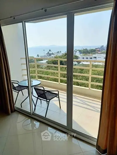 Stunning balcony view with seating overlooking lush greenery and distant water.