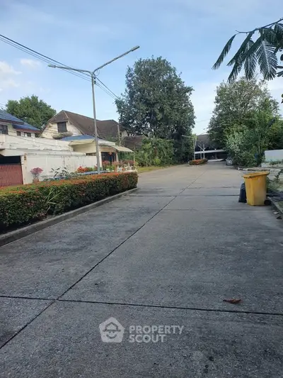 Quiet residential street with lush greenery and spacious layout.