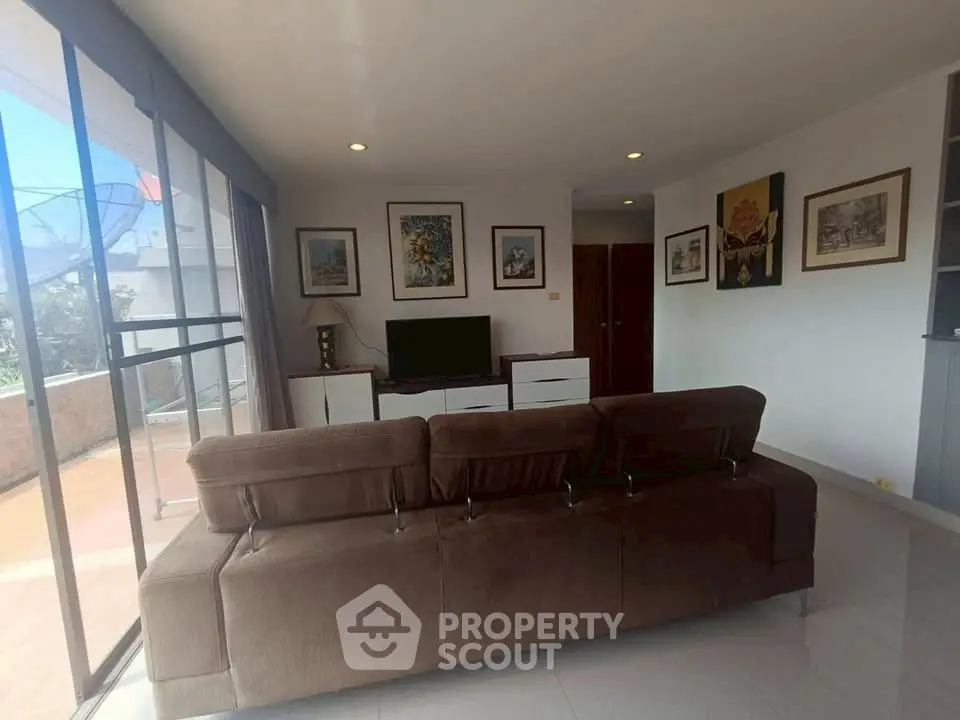 Spacious living room with large windows and modern decor, perfect for relaxation and entertainment.