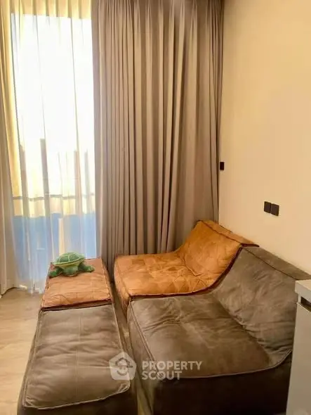 Cozy living room with plush seating and natural light through sheer curtains.