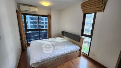 Modern bedroom with large windows and wooden flooring in urban apartment