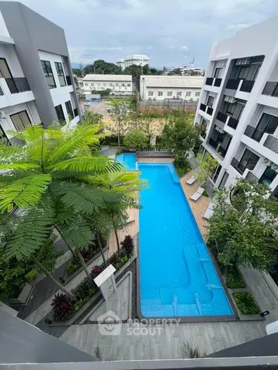 Stunning aerial view of modern apartment complex with inviting swimming pool and lush greenery.