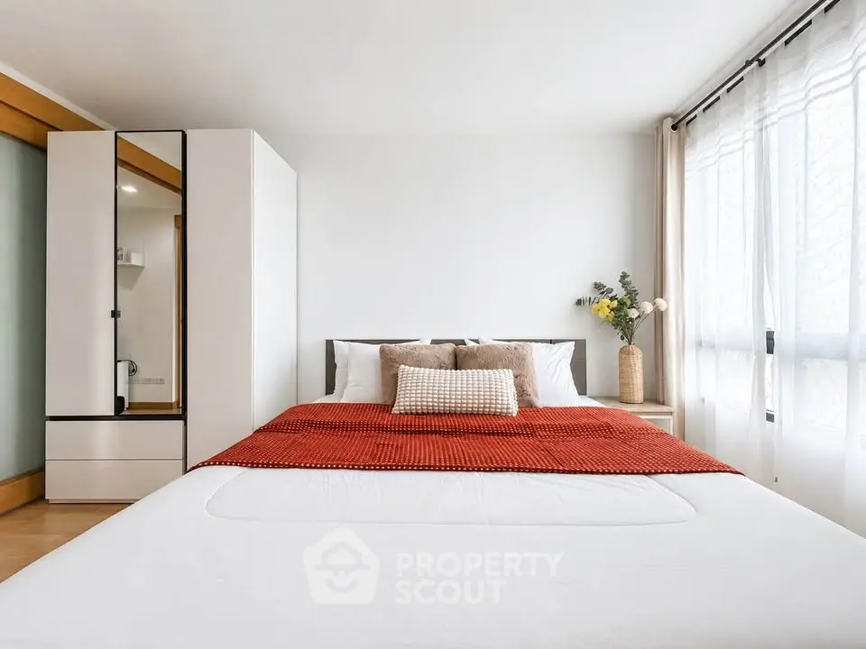 Spacious bedroom with modern decor and large window for natural light.