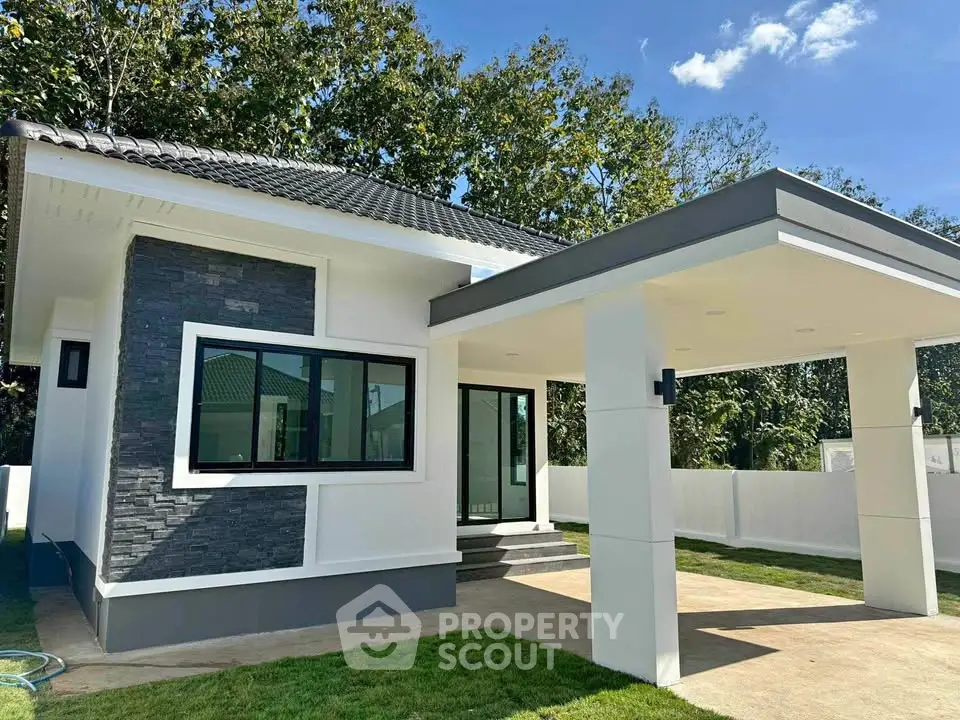 Modern single-story house with carport and stylish facade in a lush green setting.