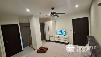 Modern bedroom with ceiling fan, sleek wardrobe, and TV on dresser, offering a cozy and functional space.