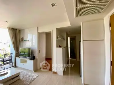 Modern living room with open layout and balcony view, featuring sleek furniture and natural light.