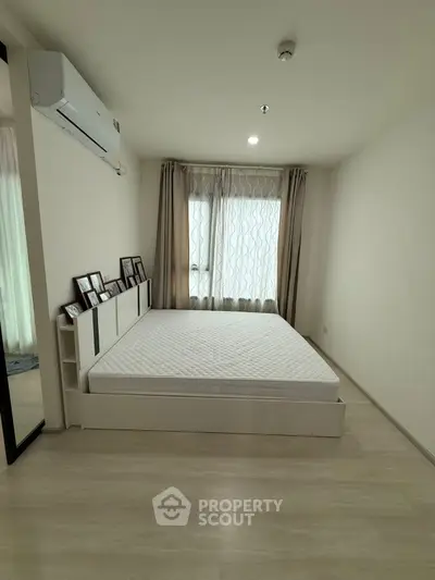 Spacious bedroom with modern decor and large window for natural light.