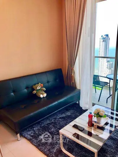 Chic living room with balcony view, modern sofa, and elegant decor in a high-rise apartment.