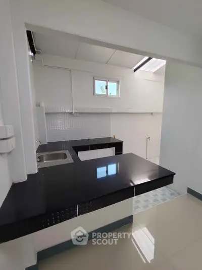 Modern kitchen with sleek black countertops and open layout design.