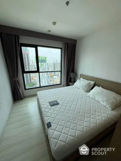 Modern bedroom with city view, featuring a large window and stylish decor.