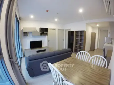 Modern living room with sleek furniture and dining area in open layout apartment.