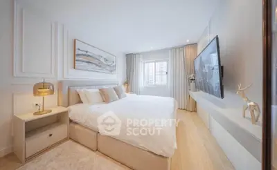 Luxurious bedroom with modern decor, large bed, and wall-mounted TV in a bright, airy space.
