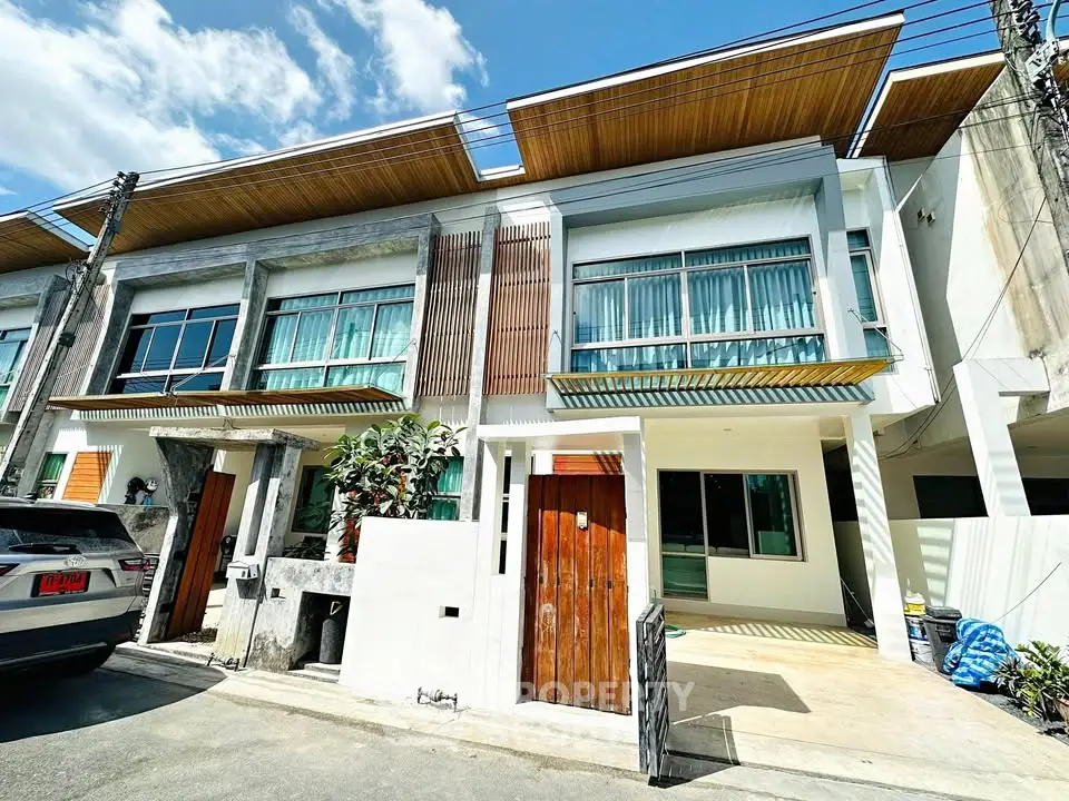Modern townhouse exterior with sleek design and large windows under a clear blue sky.