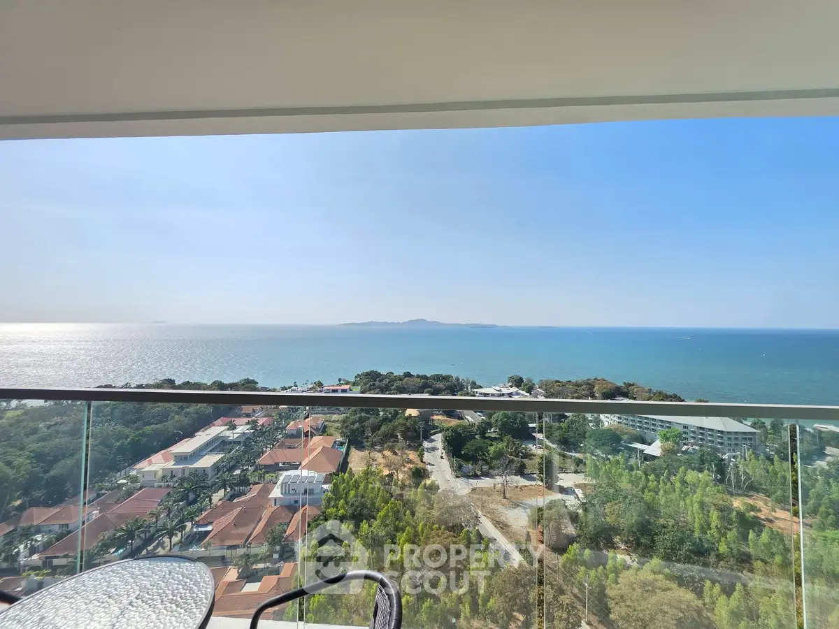 Stunning ocean view from a high-rise balcony with clear blue skies and lush greenery.