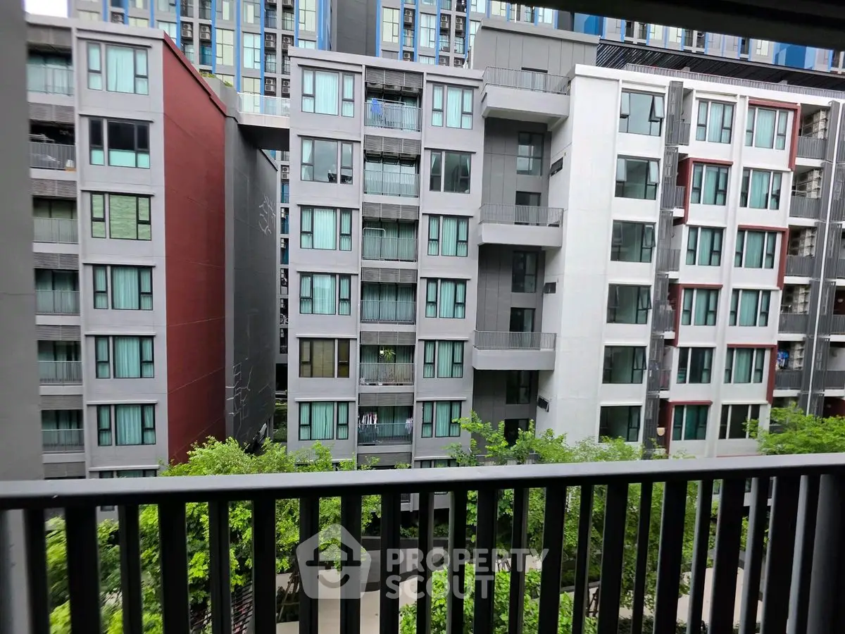Modern urban apartment building with balconies and lush greenery view.