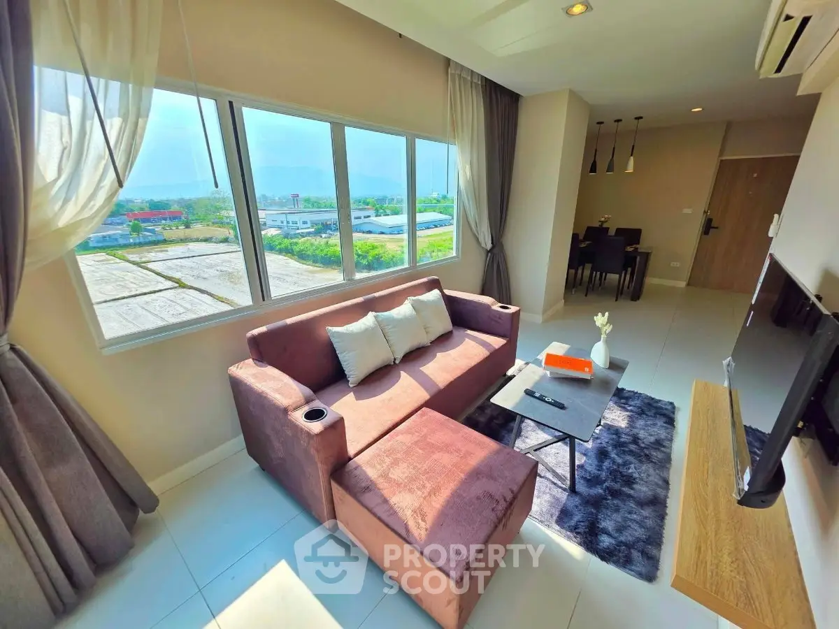 Modern living room with large window and stylish furniture, offering a bright and inviting atmosphere.