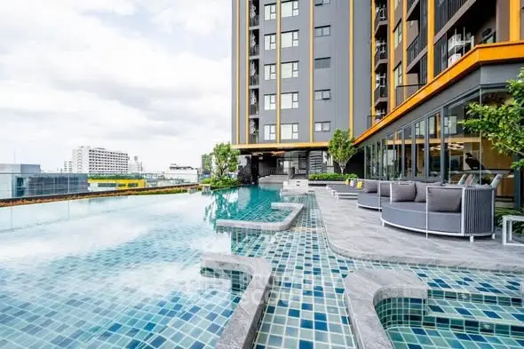Luxurious rooftop pool with city view and modern seating area in high-rise building.