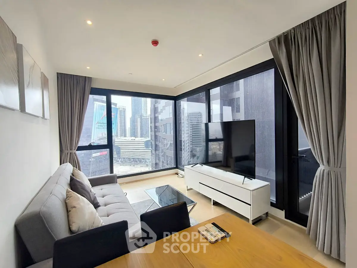 Modern living room with city view, featuring sleek furniture and large windows for natural light.