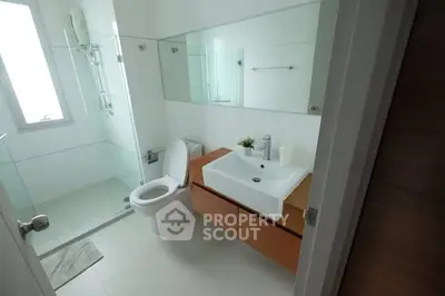 Modern bathroom with glass shower and sleek vanity in a bright, minimalist design.