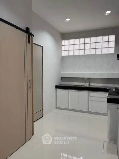 Modern kitchen with sleek white cabinets and black countertops in minimalist design.