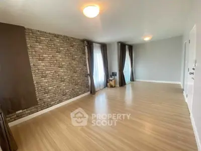 Spacious empty living room with wooden flooring and stone accent wall