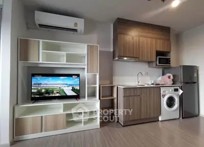 Modern studio apartment with compact kitchen and entertainment area, featuring washing machine and air conditioning.