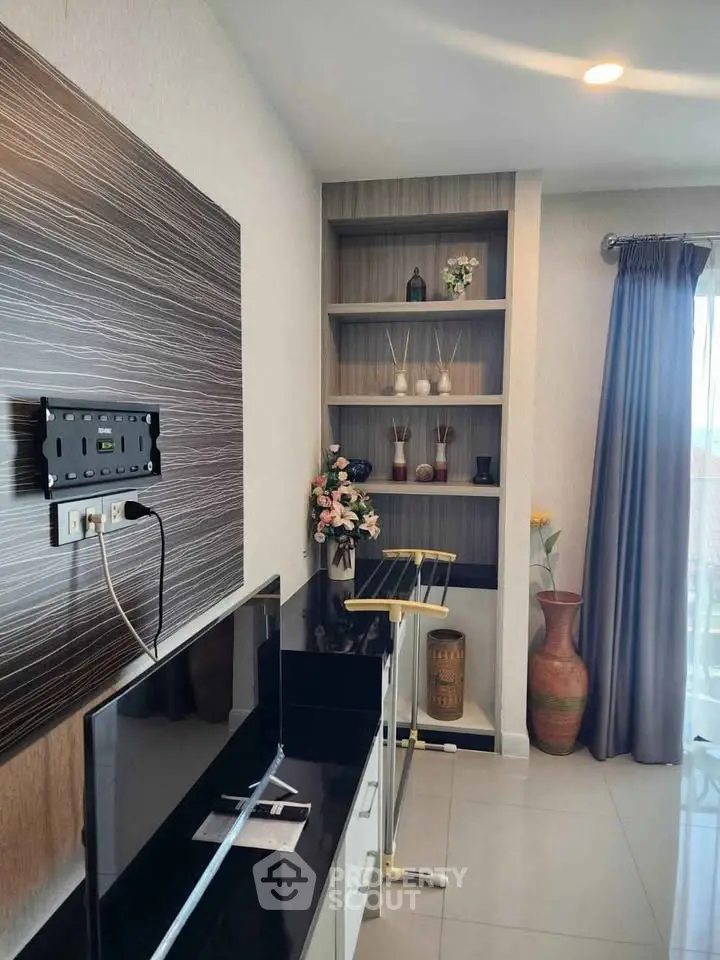 Modern living room with stylish decor and built-in shelving, featuring elegant vases and a wall-mounted TV setup.