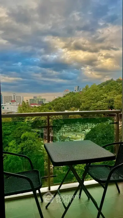 Stunning balcony view with lush greenery and city skyline under dramatic skies.