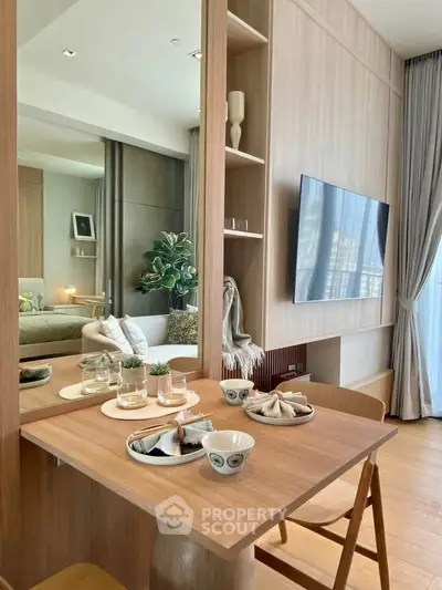 Modern living room with stylish dining area and wall-mounted TV, featuring elegant decor and natural light.