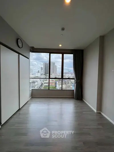 Spacious empty room with large window offering stunning city view, perfect for customization.