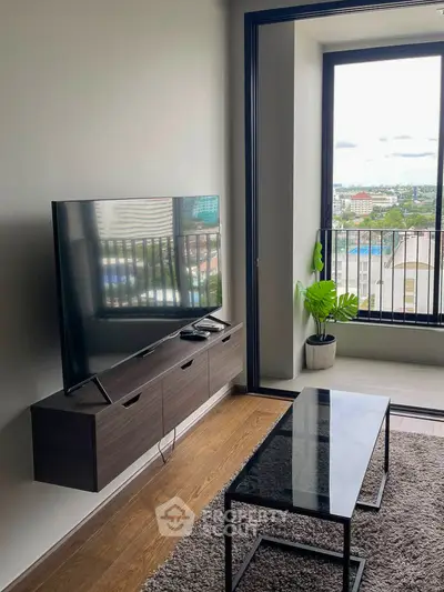 Modern living room with large TV and balcony view in urban apartment