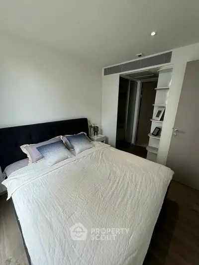 Modern bedroom with stylish decor and ample natural light, featuring a comfortable bed and sleek storage solutions.