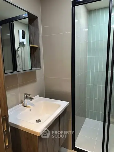 Modern bathroom with sleek shower and stylish sink in contemporary apartment.