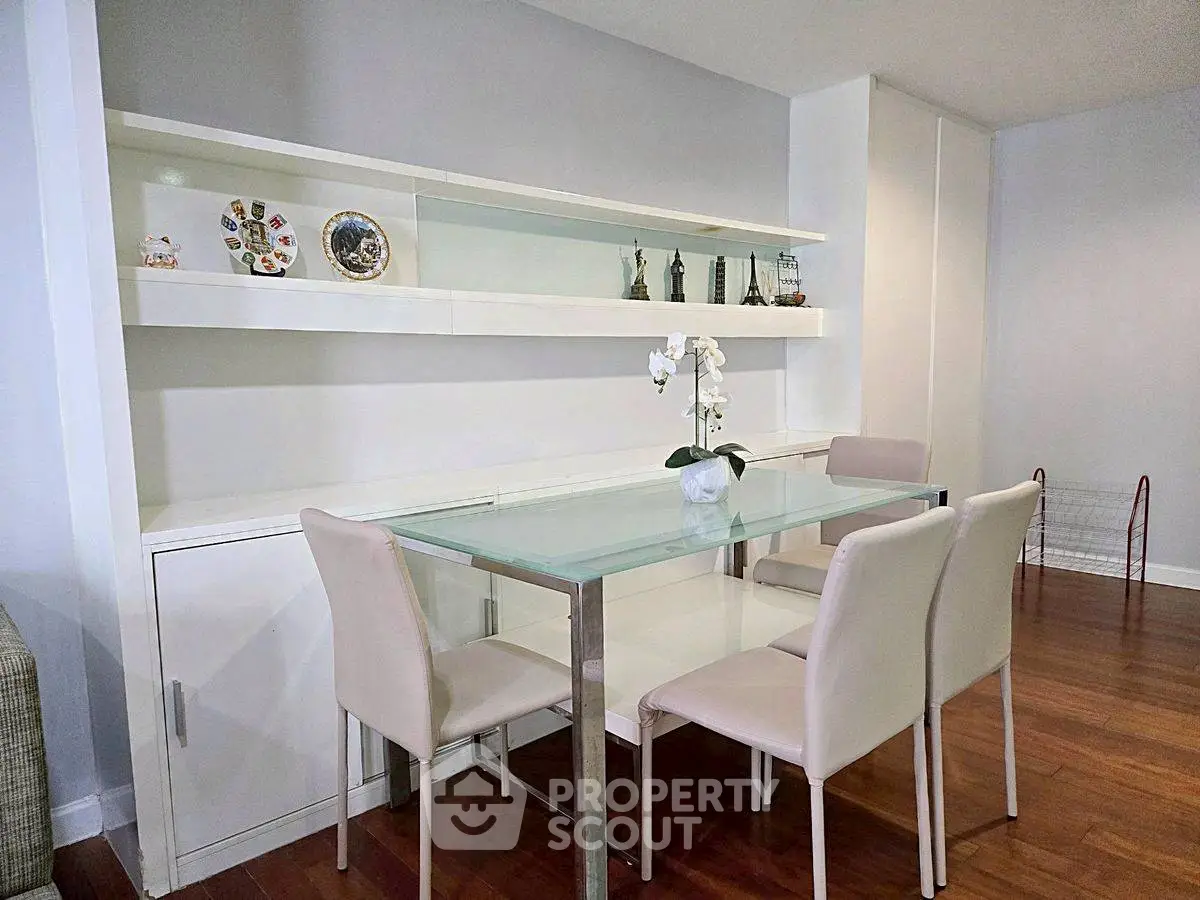 Modern dining area with glass table and elegant shelving in stylish apartment.