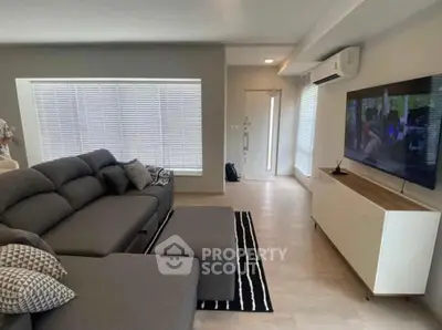 Modern living room with sleek furniture and large TV, perfect for relaxation and entertainment.