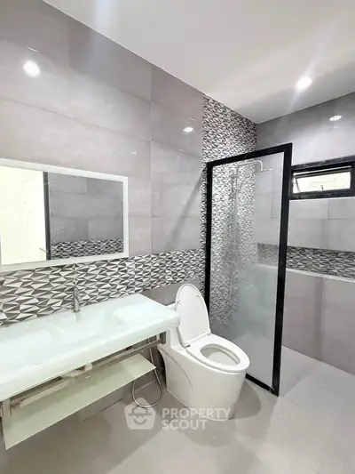 Modern bathroom with sleek design, featuring a glass shower enclosure and stylish tile accents.