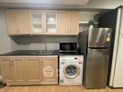 Modern kitchen with wooden cabinets, washing machine, microwave, and stainless steel fridge.