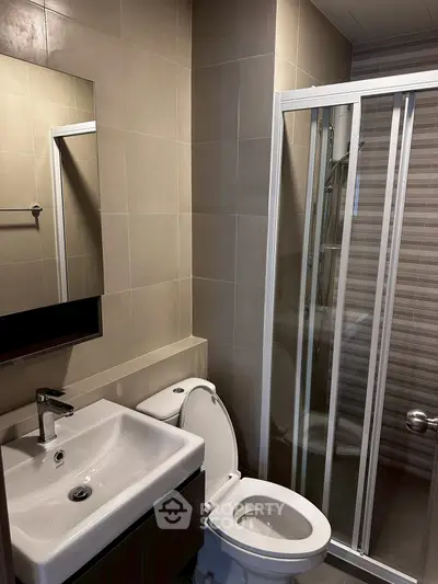 Modern bathroom with sleek fixtures and glass shower enclosure.