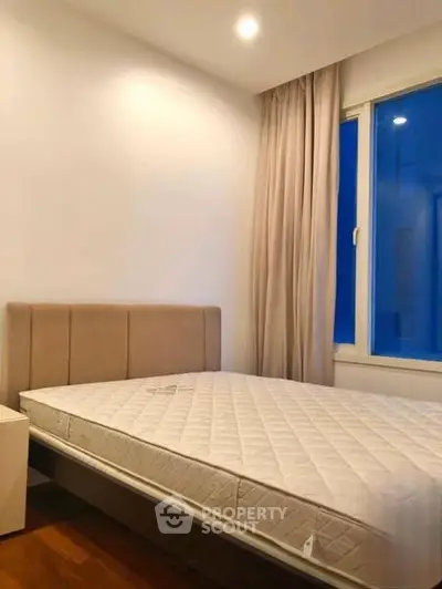 Cozy bedroom with large window and modern furnishings in a stylish apartment.
