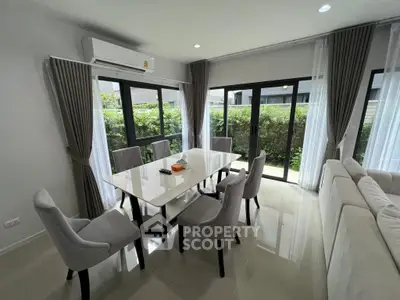 Elegant dining area with modern furniture and large windows offering garden views.