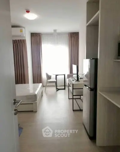 Modern studio apartment with natural light, featuring a compact kitchen and cozy living area.