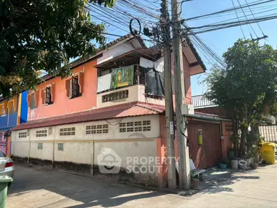 Charming two-story house with vibrant exterior and lush greenery, perfect for family living.
