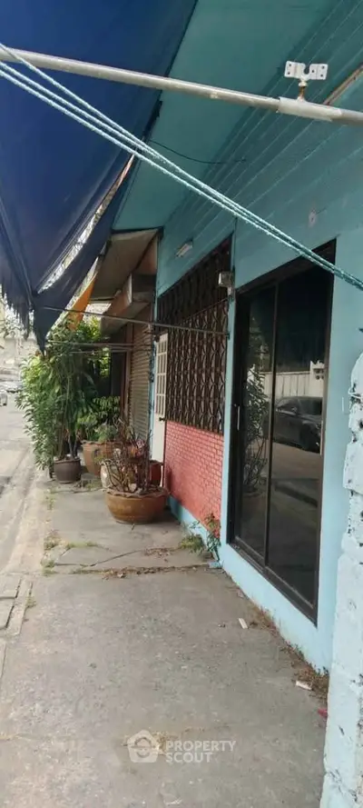 Charming street view of a colorful building with potted plants and awning.