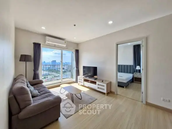 Modern living room with city view, cozy sofa, and sleek TV setup.