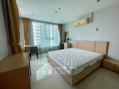 Spacious bedroom with modern furnishings and large window offering natural light.