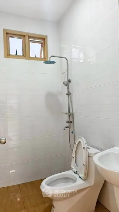 Modern bathroom with sleek shower and white fixtures in a minimalist design.