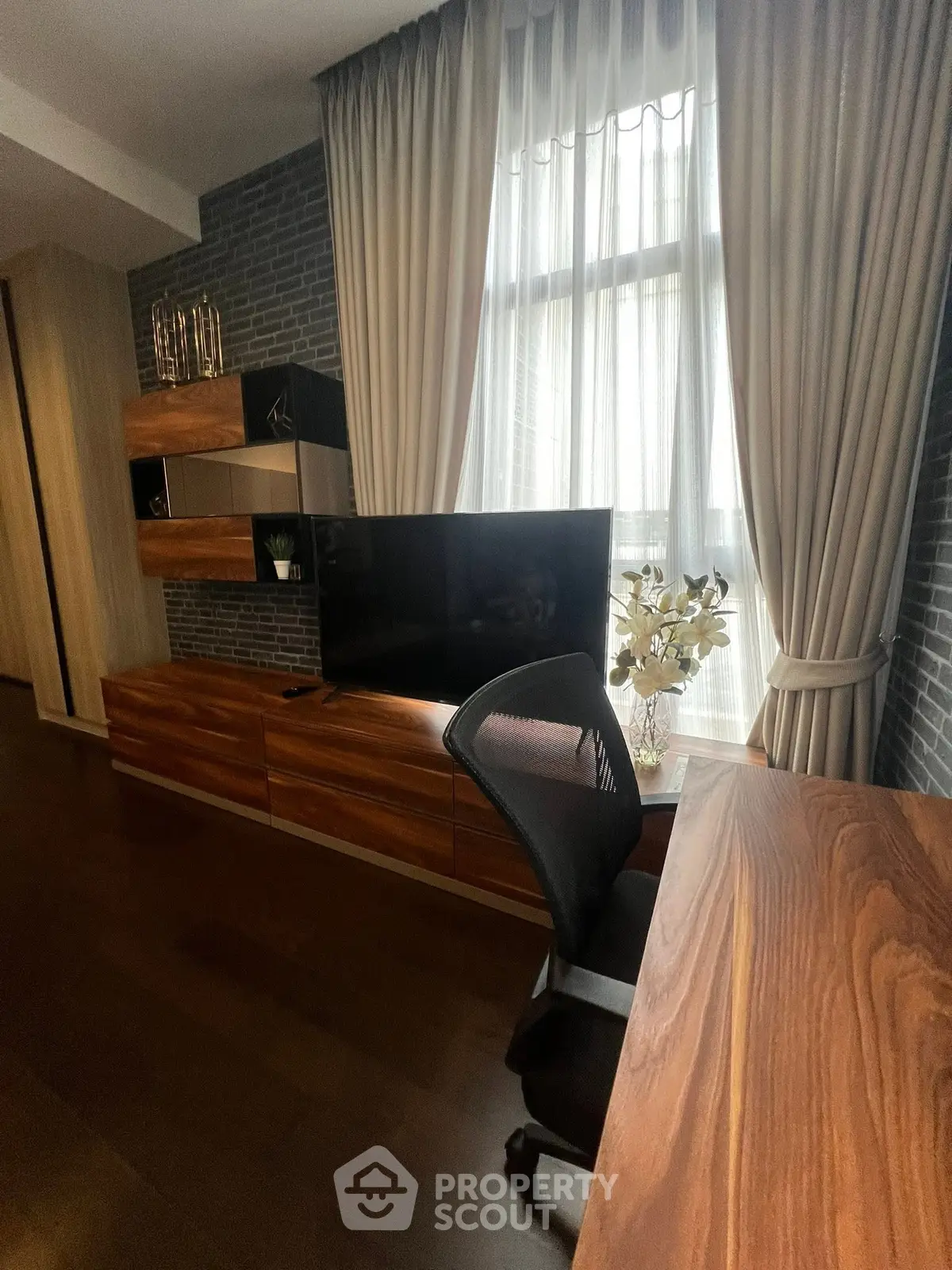 Modern study room with elegant wooden furniture and large window with curtains.